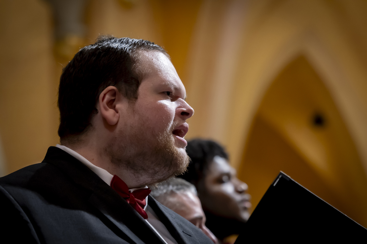 A man sings passionately in profile view.