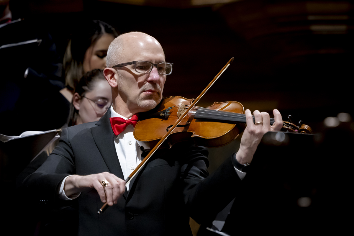 A man plays the violin with focused expression.