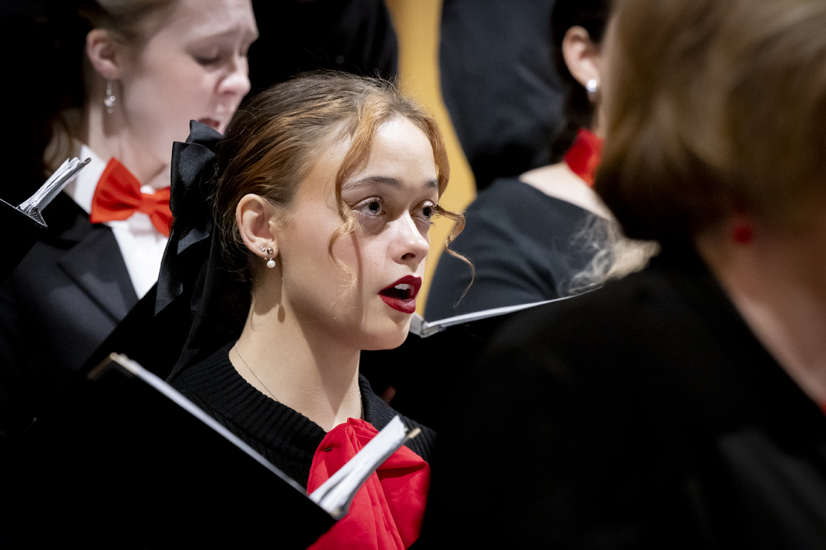 A young woman sings while holding sheet music.