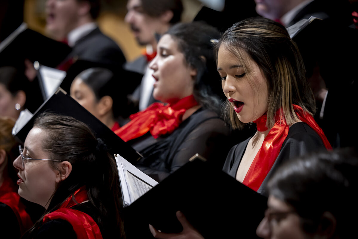 A focused view of choir members singing in harmony, holding songbooks.