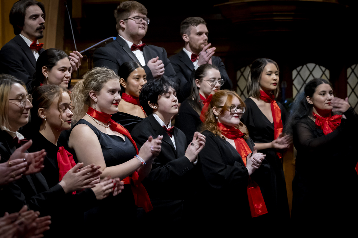 Choir members clap together.