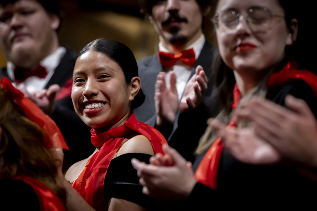 A young woman in the choir smiles warmly.