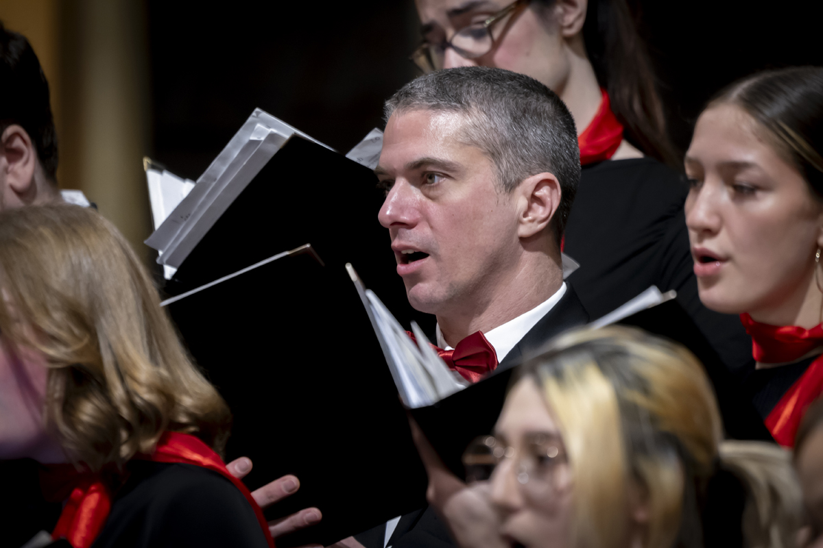 A male choir member sings with intensity during a choral performance.