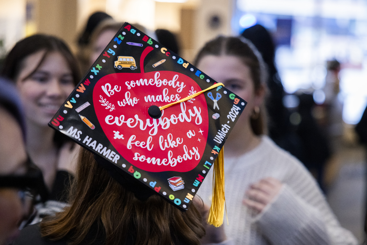 A decorated graduation cap features a red apple with an inspirational quote.