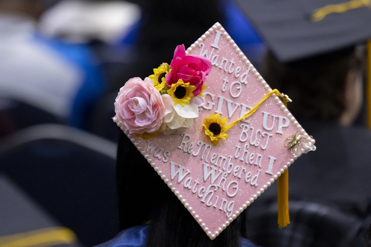 A pink graduation cap decorated with flowers and an inspirational message about perseverance.