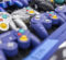 A variety of purple and silver GameCube controllers displayed on a table.