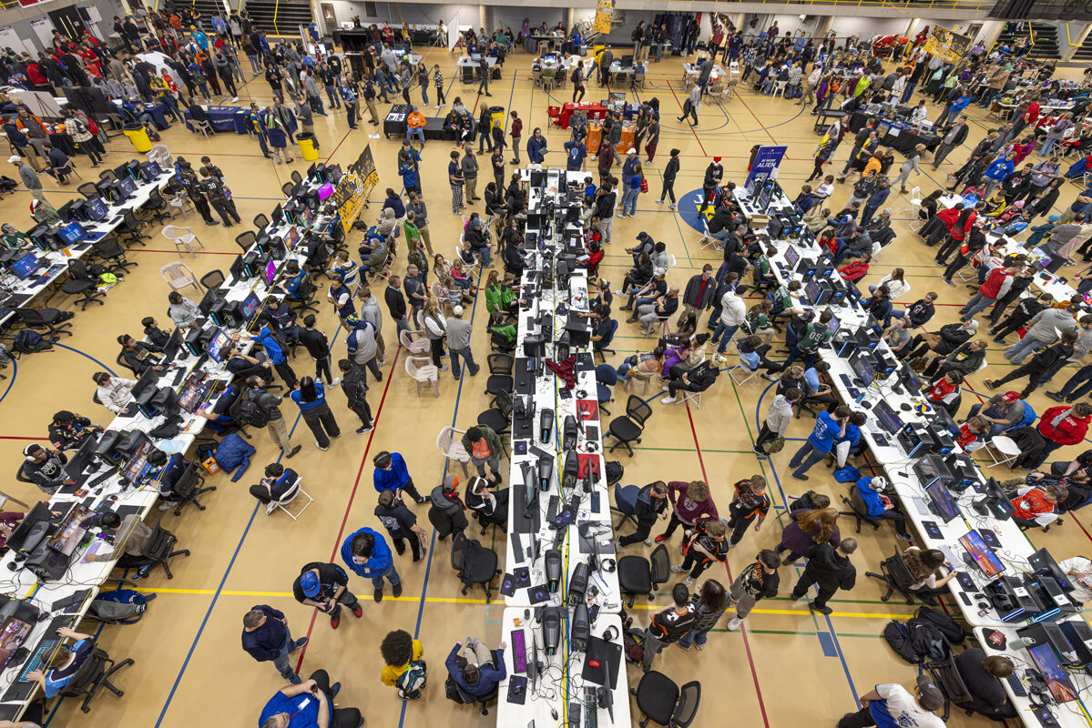 An overhead view of a busy esports arena with rows of tables and gaming setups.