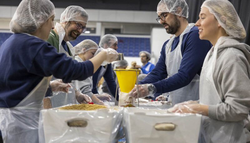 A group of UM-Flint volunteers in hairnets packaging food.