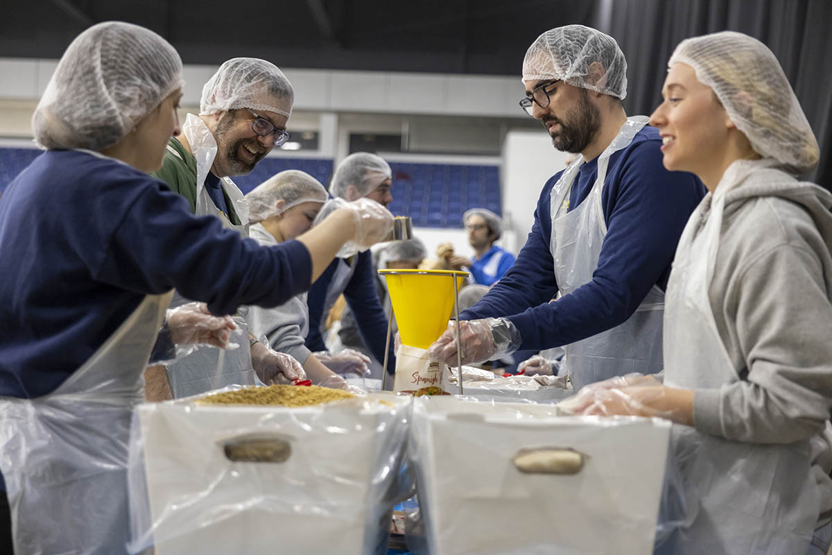 A group of UM-Flint volunteers in hairnets packaging food.