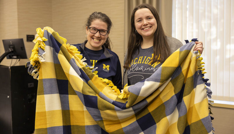 Two UM-Flint volunteers posing with the blanket they tied