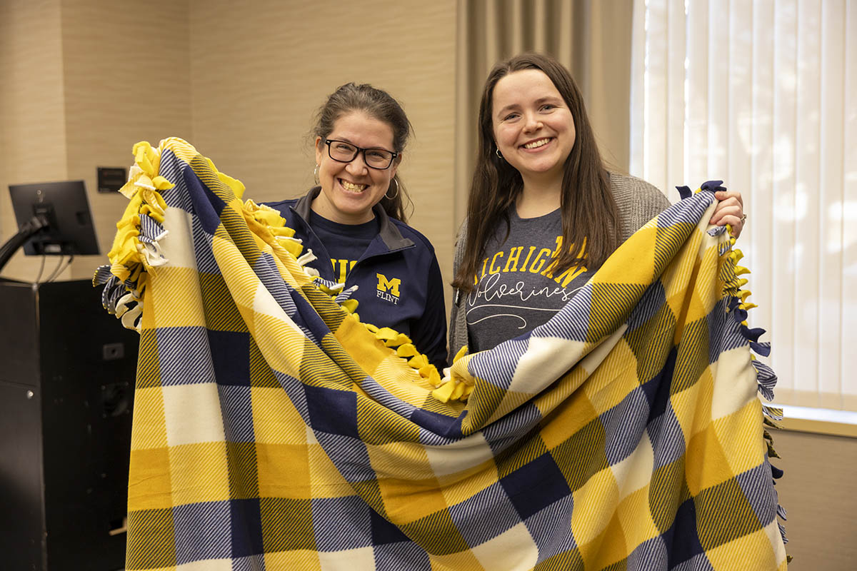 Two UM-Flint volunteers posing with the blanket they tied