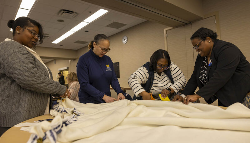 A group of UM-Flint volunteers working on a blanket