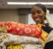 A UM-Flint staff member smiling while holding a stack of blankets made during MLK Day.