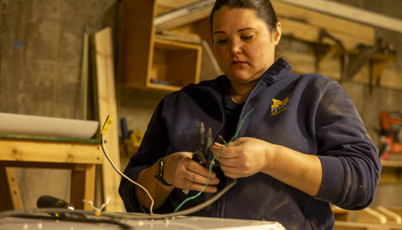 A UM-Flint volunteer working with wires in a workshop