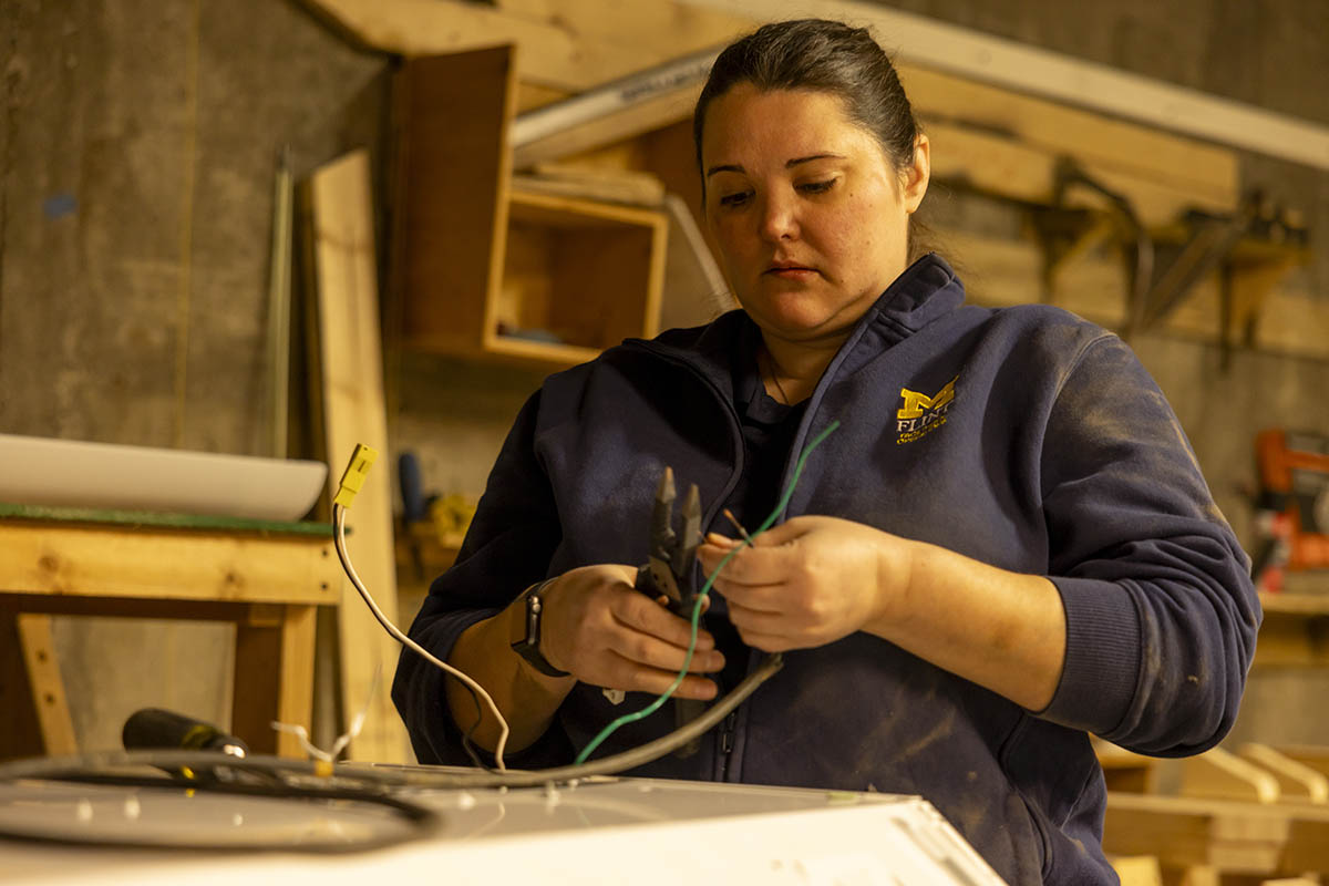 A UM-Flint volunteer working with wires in a workshop