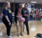 Two female UM OT students assist a stroke patient with bowling. Patient holds a light pink bowling ball.