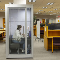 A student working on her laptop inside a quiet study pod in the library.