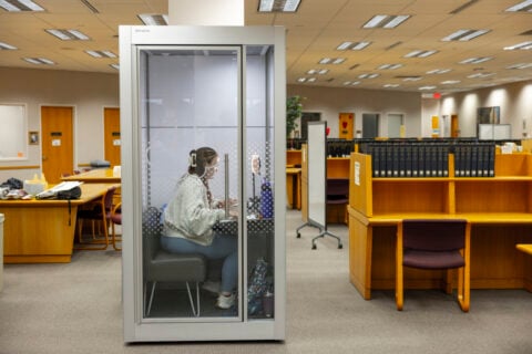 A student working on her laptop inside a quiet study pod in the library.