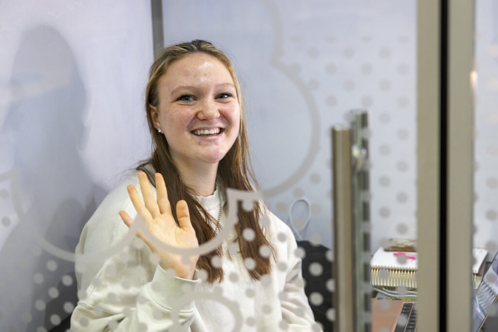 A student waving in the study pod.