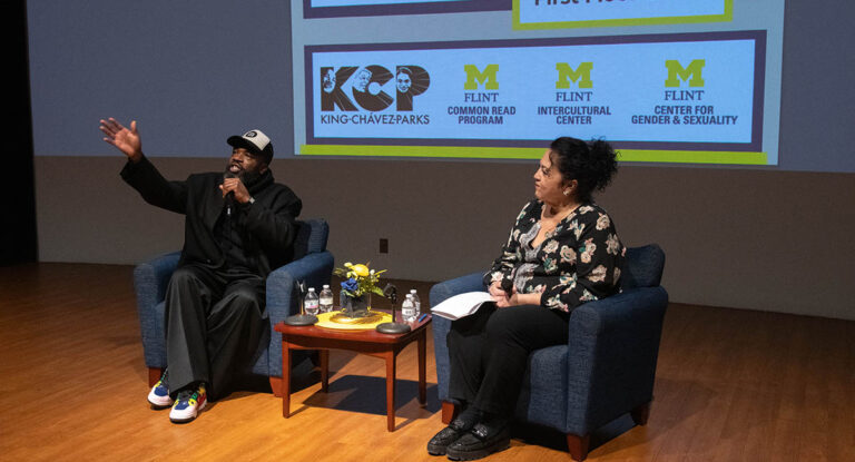 Two speakers seated on stage