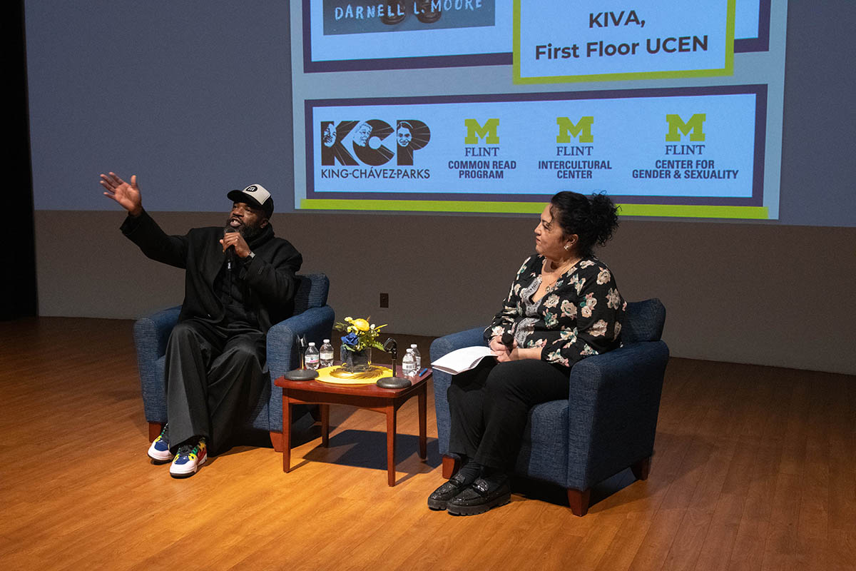 Two speakers seated on stage