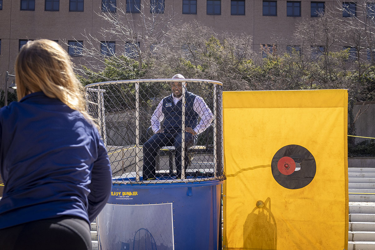 A staff member sitting over a dunk tank while another person throws.