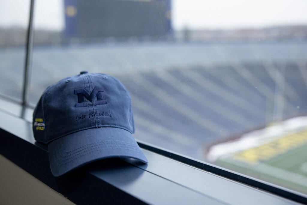 A U-M branded ballcap sitting on a windowsill inside Michigan stadium. 