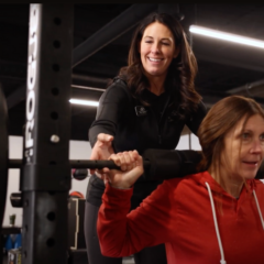 Amber Schlemmer spotting a patient while the patient performs a back squat with a barbell