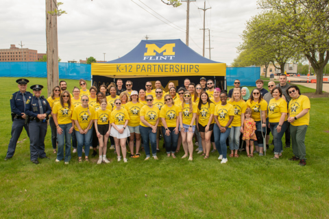 A group of volunteers standing in front of a tent on a grass field for Officer Friendly Day 2024
