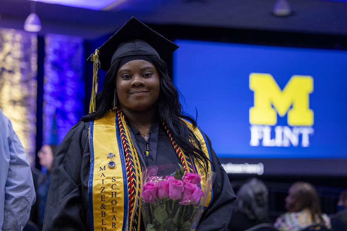 A graduating student holding flowers