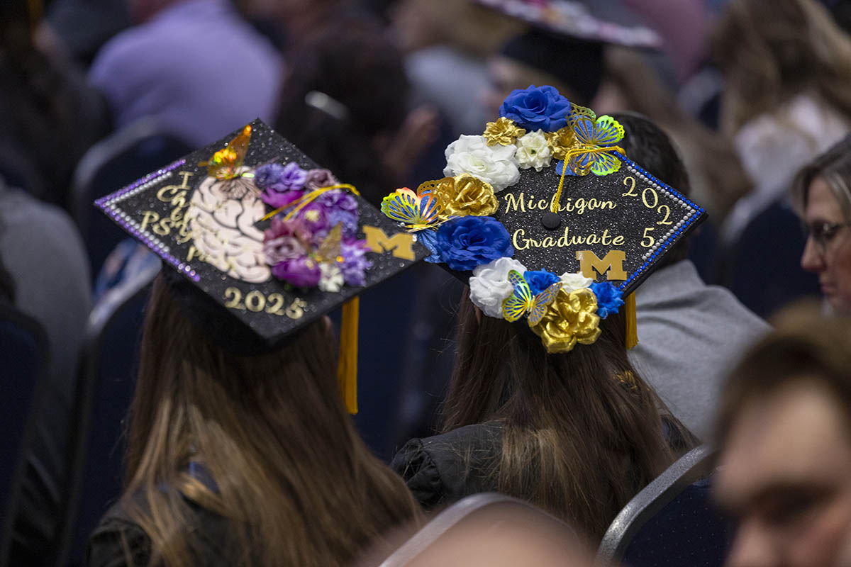 Two decorated graduation caps. One reads, Chi Psy 2025 with a picture of a brain. The other reads Michigan Graduate 2025.
