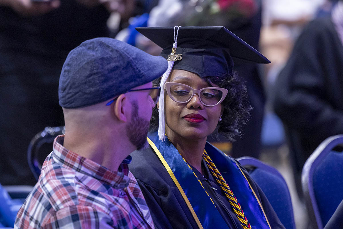 A graduating student sitting with a loved one in the crowd.