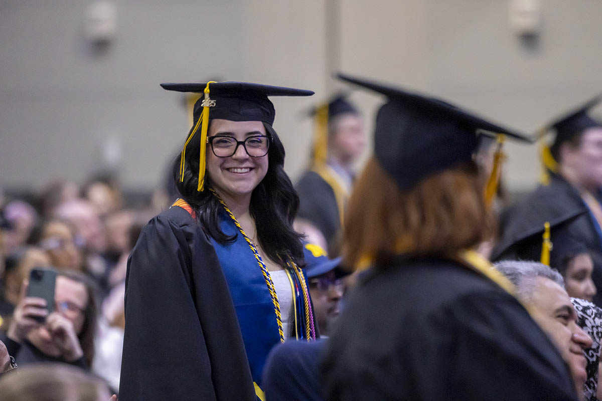 A student walking to the stage smiling for the camera.