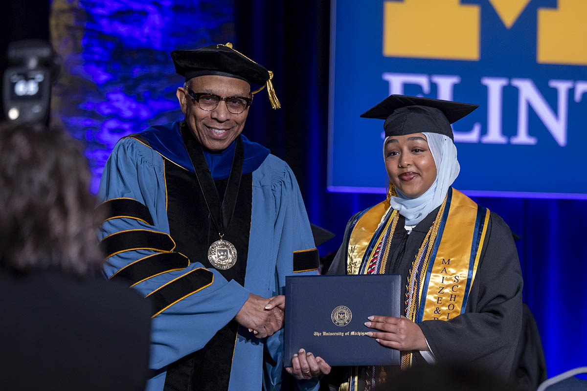 Lina Azeim receiving her diploma cover from Chancellor Laurence Alexander.