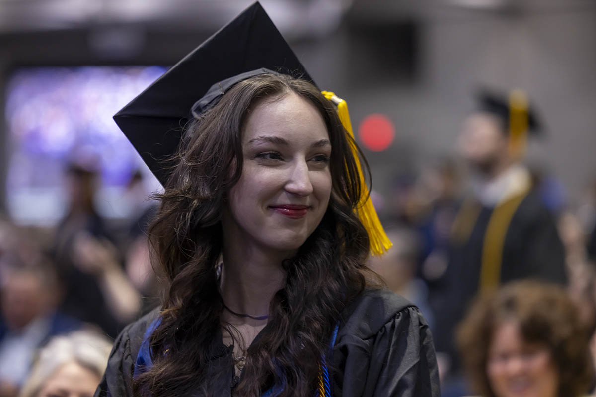 A student smiling while standing in the crowd.