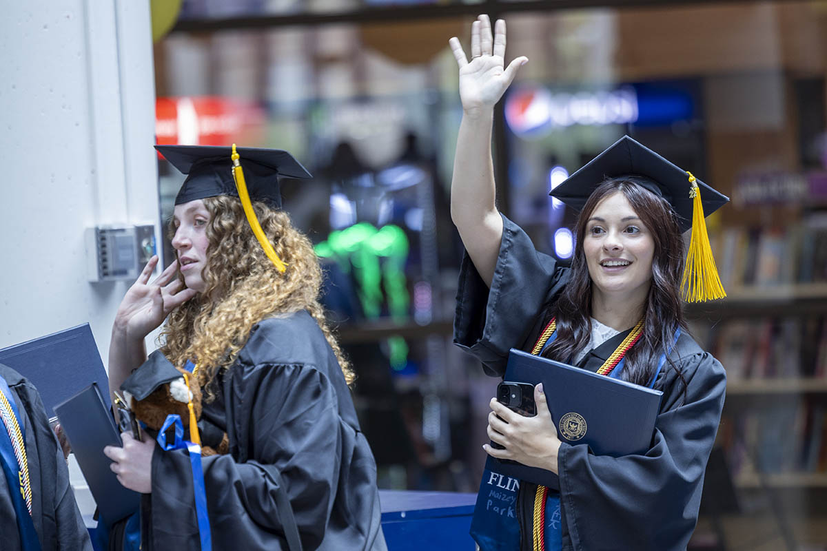 Students waving and smiling in the University Pavilion after Commencement.