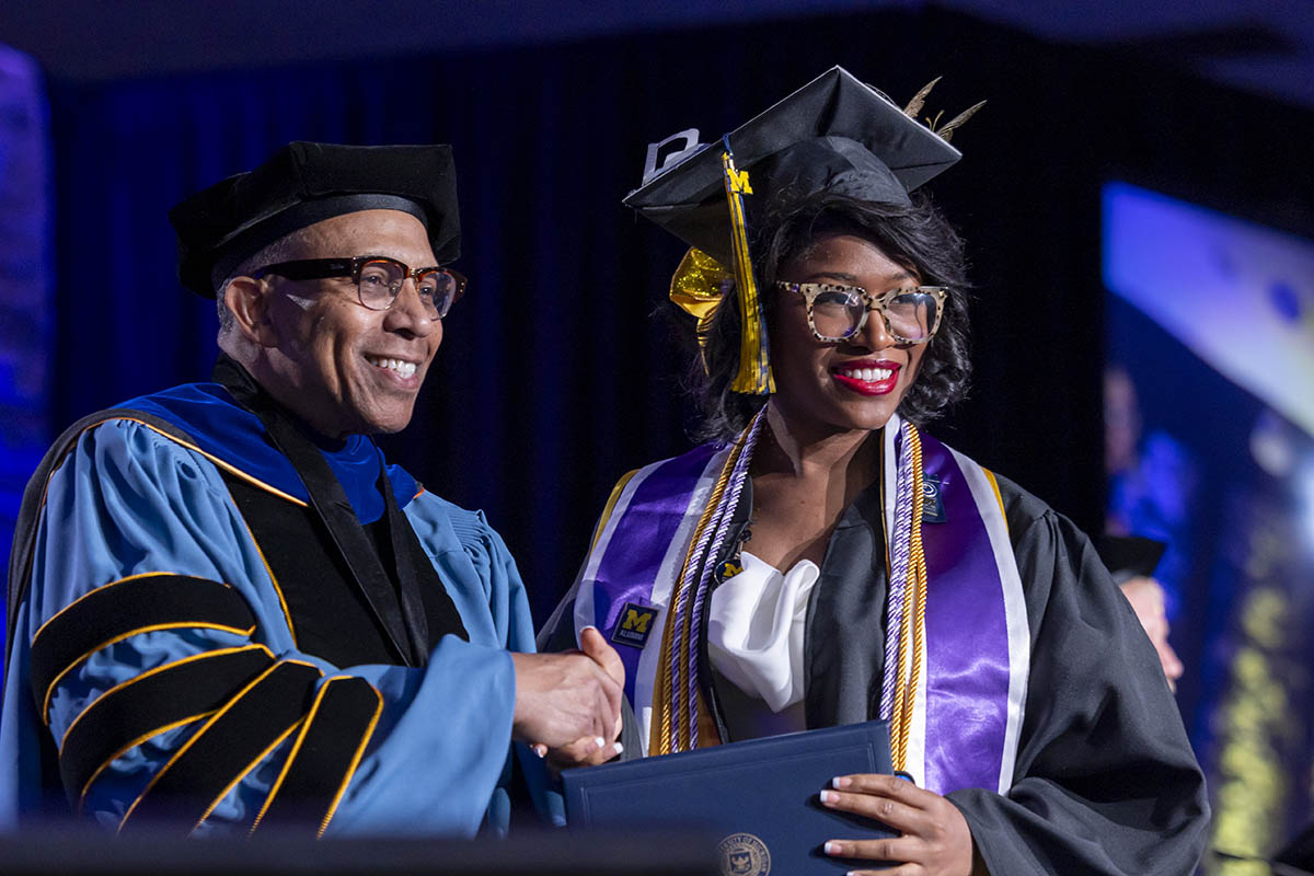A student shaking hands with Chancellor Alexander receiving her diploma on stage.