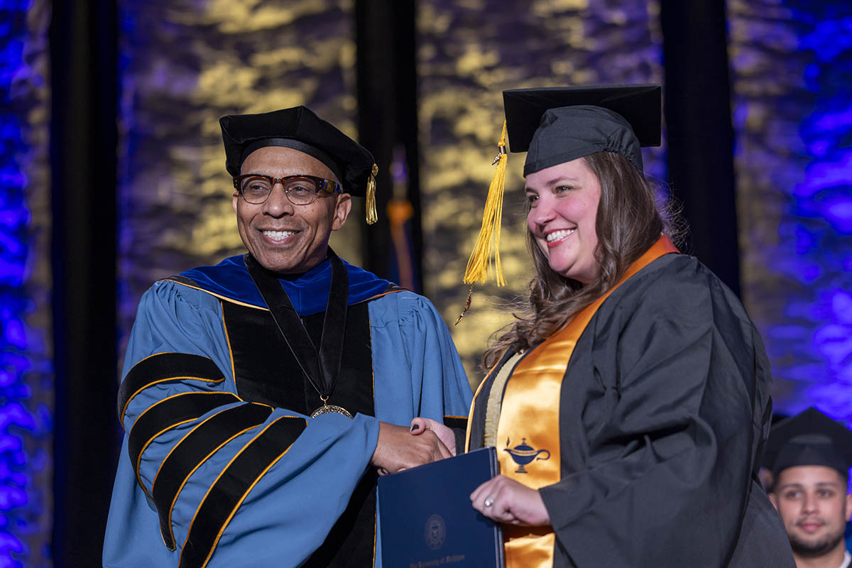 A student shaking hands with Chancellor Alexander receiving her diploma on stage.