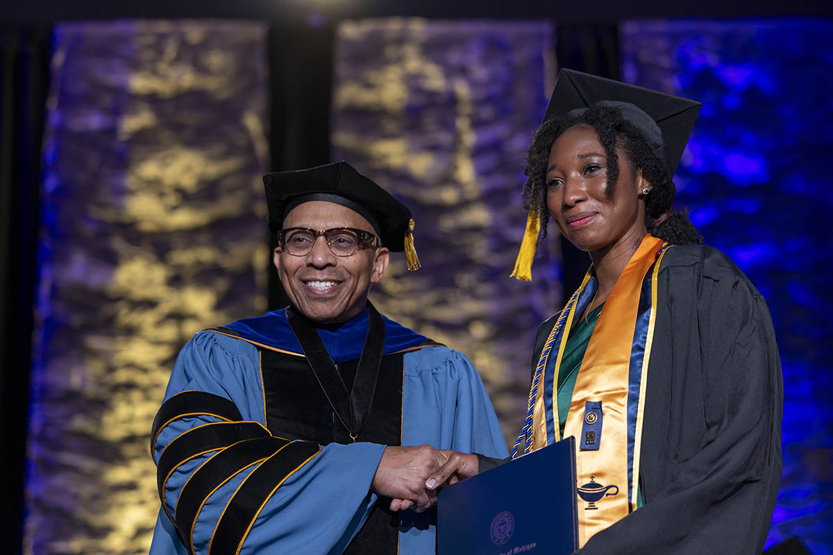A student shaking hands with Chancellor Alexander receiving her diploma on stage.