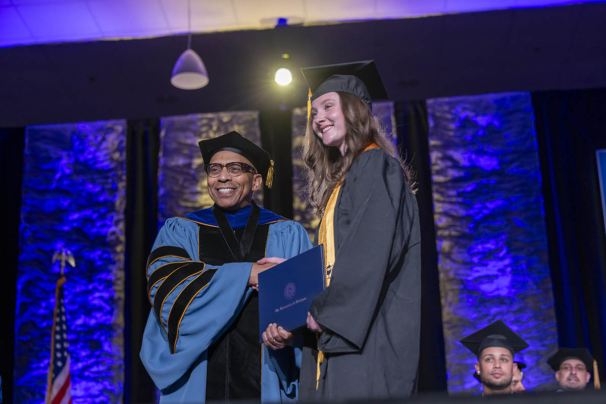 A student shaking hands with Chancellor Alexander receiving her diploma on stage.