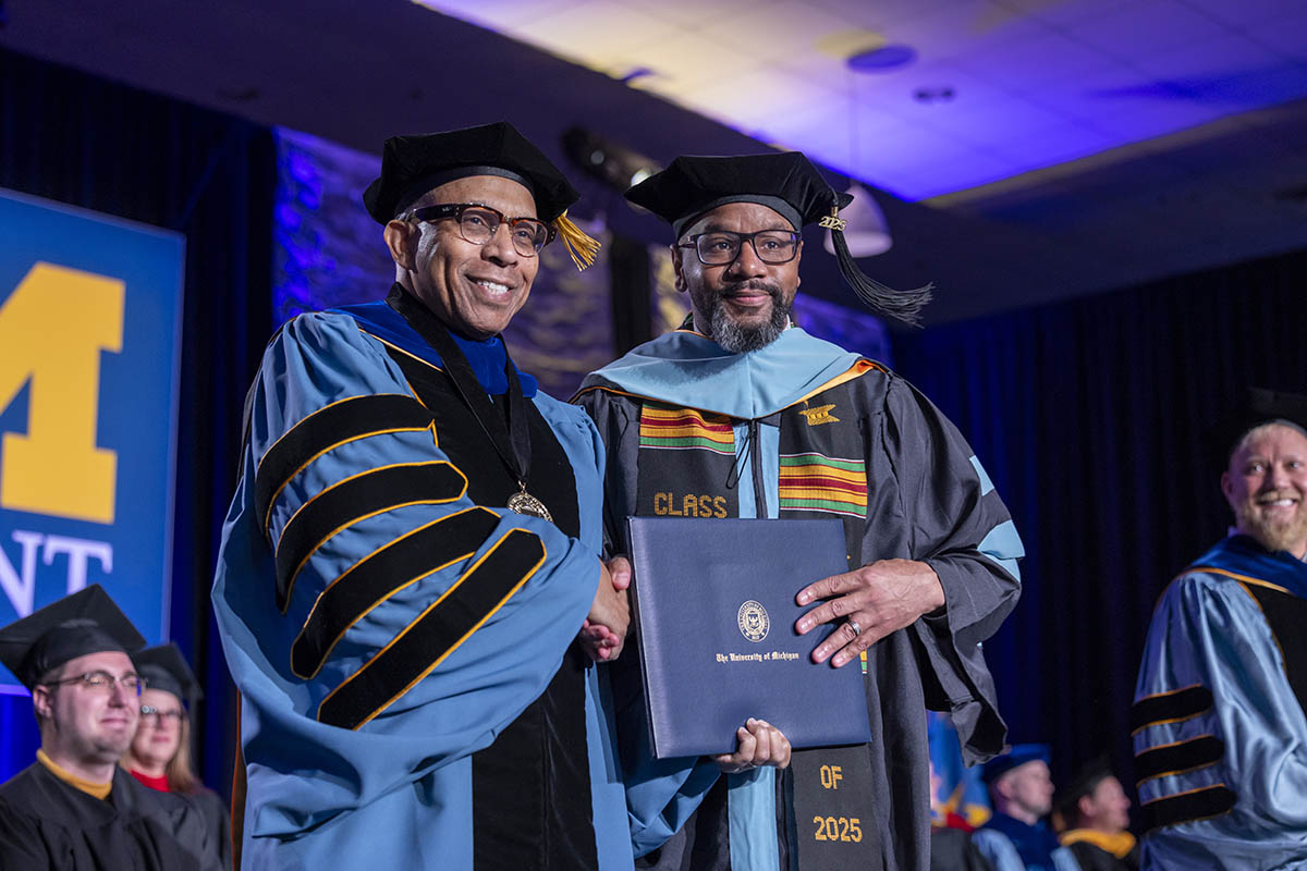 Chancellor Alexander shaking hands with a graduating student on stage.