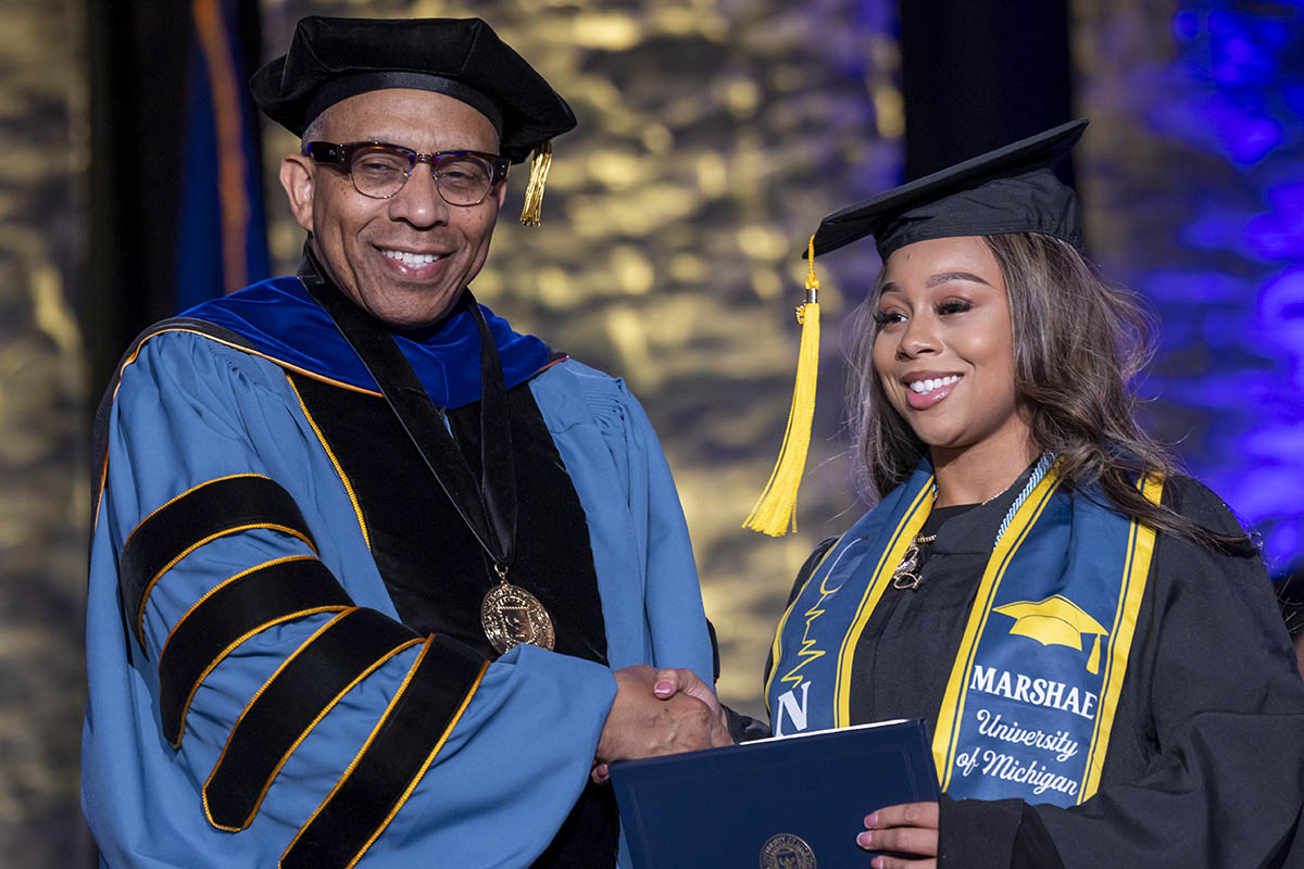 A student shaking hands with Chancellor Alexander receiving her diploma on stage.