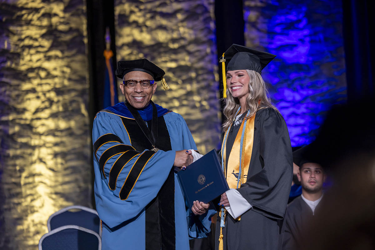 A student shaking hands with Chancellor Alexander receiving her diploma on stage.