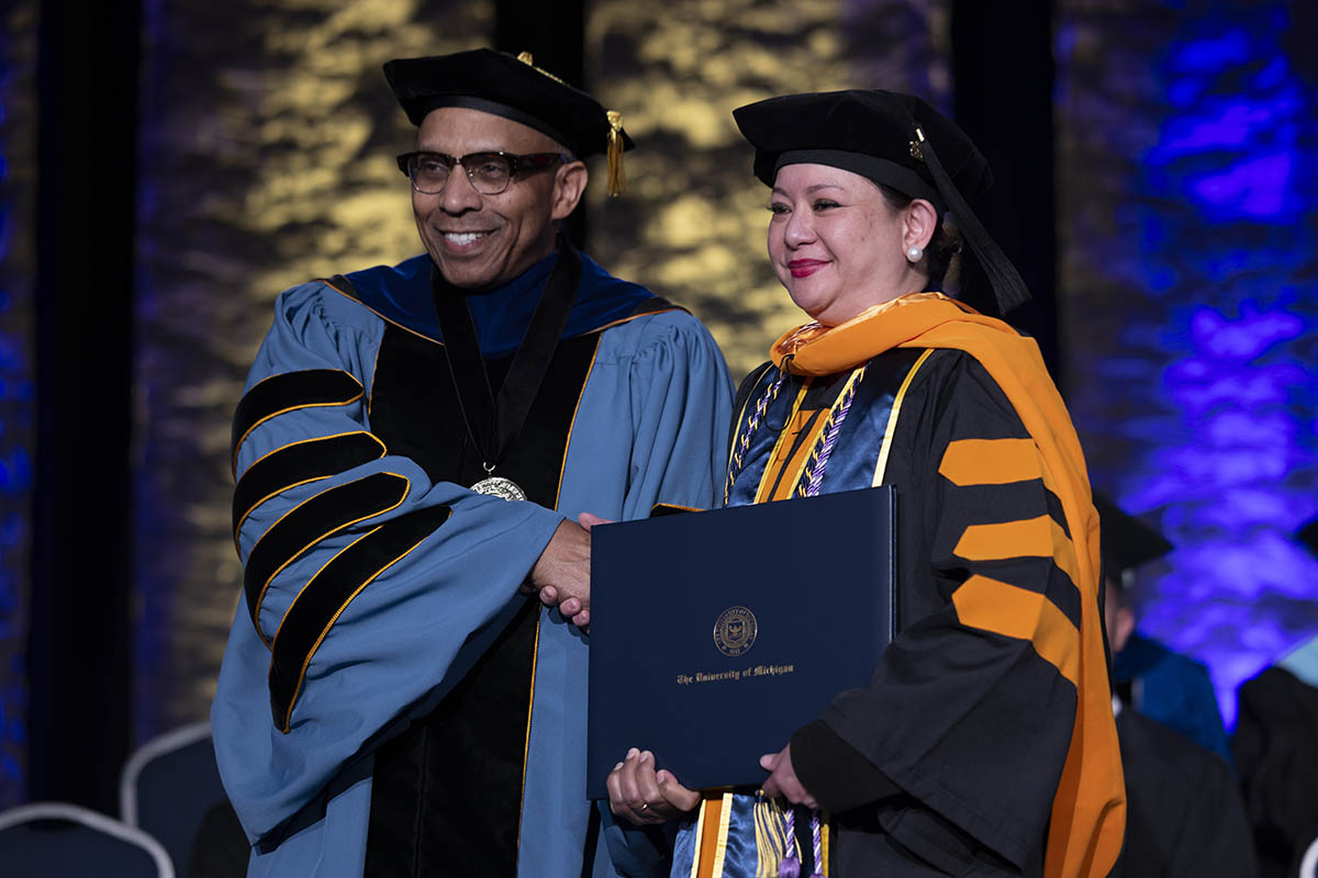 A student shaking hands with Chancellor Alexander receiving her diploma on stage.