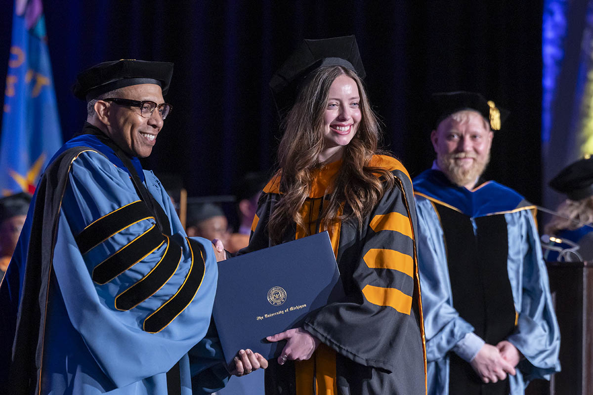 A student shaking hands with Chancellor Alexander receiving her diploma on stage.