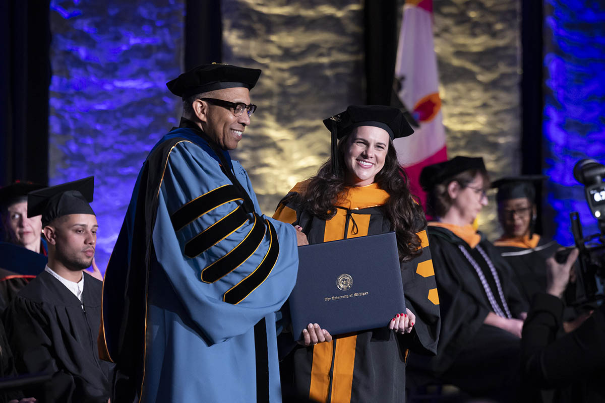 A student shaking hands with Chancellor Alexander receiving her diploma on stage.