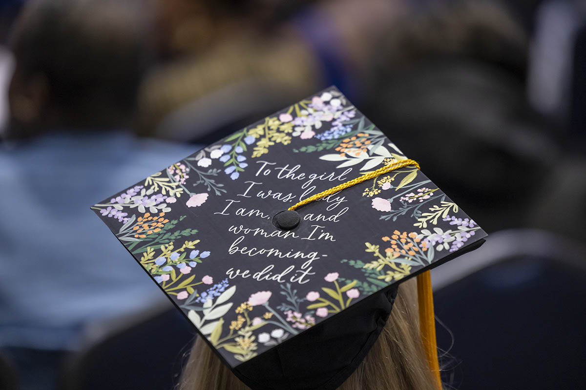 A decorated graduation cap that says "to the girl I was, the lady I am, and the woman I'm becoming ... we did it."