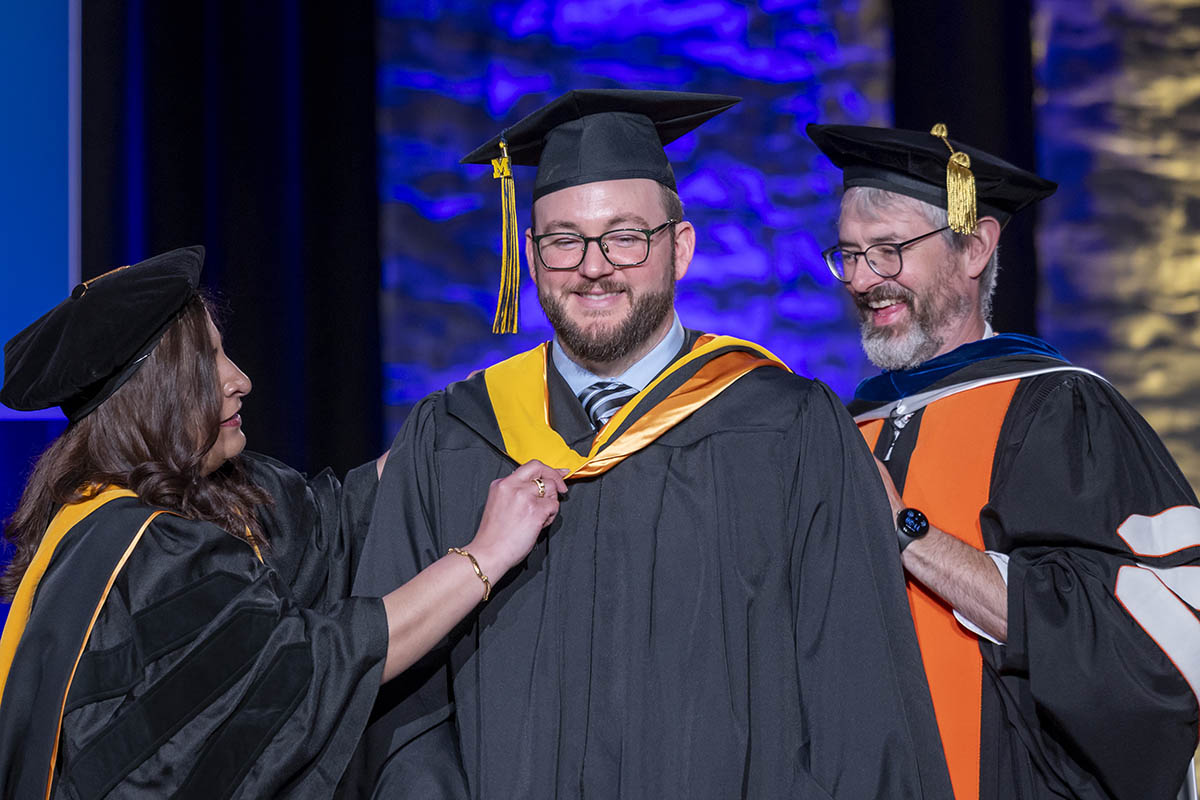 A graduating student being arrayed with a hood.