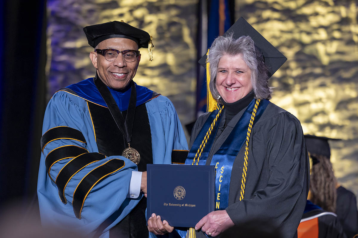 A student receiving her diploma on stage from Chancellor Laurence Alexander.