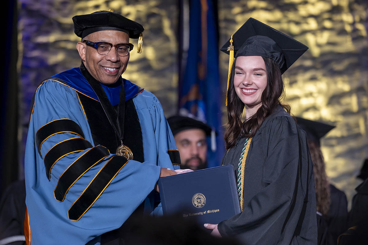 A student receiving her diploma on stage from Chancellor Laurence Alexander.